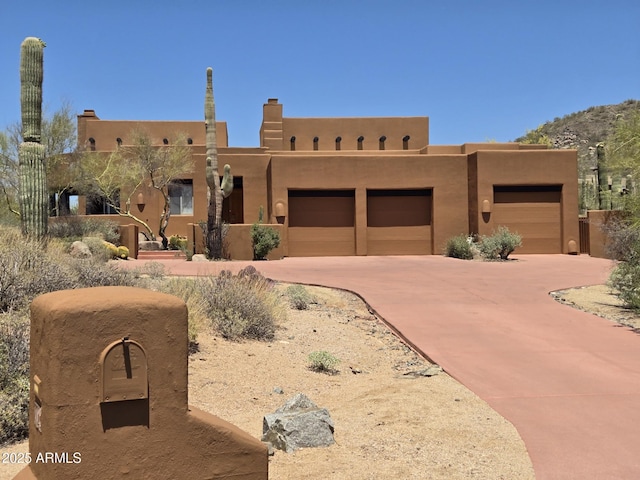 7728 E Mary Sharon Dr, Scottsdale, AZ 85266 - pueblo-style home featuring an attached garage, concrete driveway, and stucco siding