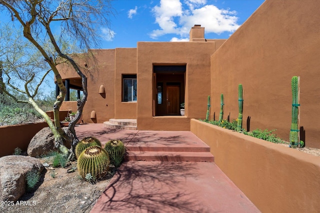 7728 E Mary Sharon Dr, Scottsdale, AZ 85266 - view of exterior entry featuring a chimney and stucco siding