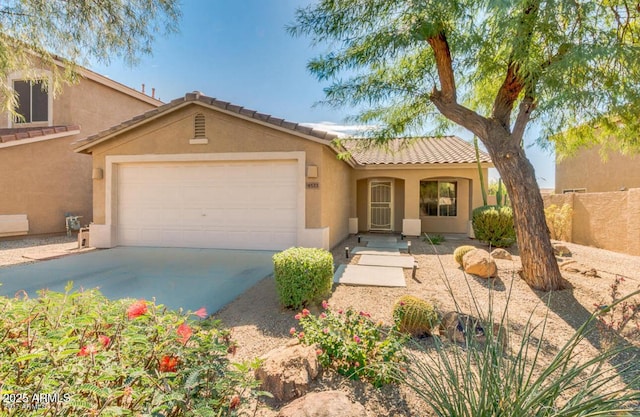 view of front of property with fence, a tile roof, concrete driveway, stucco siding, and an attached garage