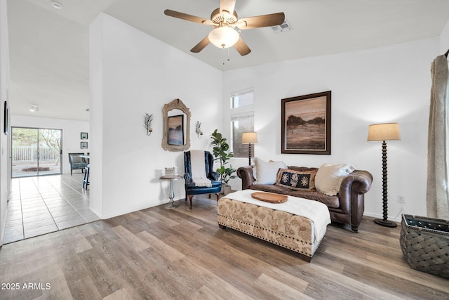 sitting room with ceiling fan, visible vents, baseboards, and wood finished floors