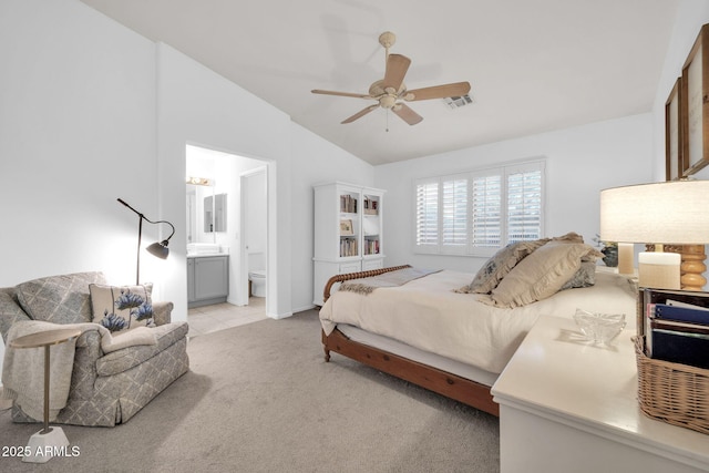 bedroom with visible vents, ceiling fan, light colored carpet, vaulted ceiling, and ensuite bath