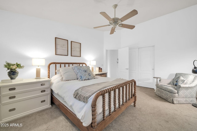 bedroom with a closet, light colored carpet, and a ceiling fan