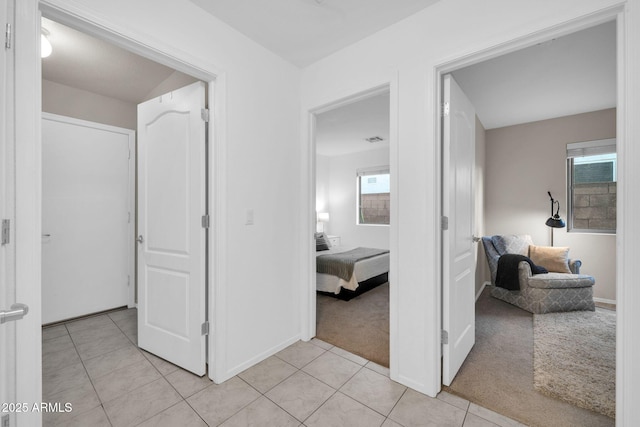 hallway featuring light tile patterned floors, light colored carpet, and visible vents