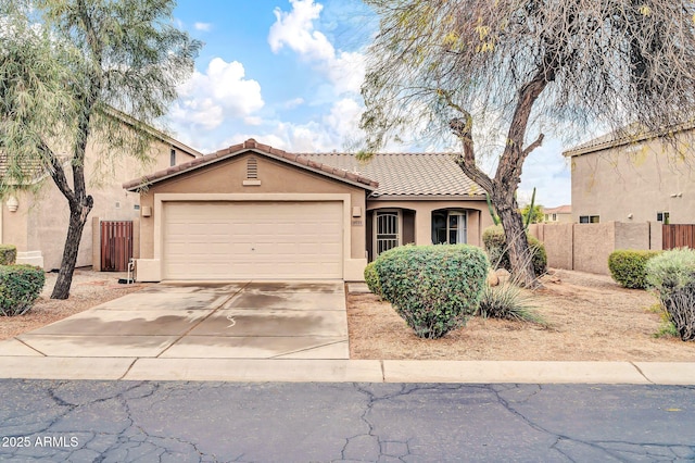 view of front of home featuring stucco siding, concrete driveway, a garage, and fence