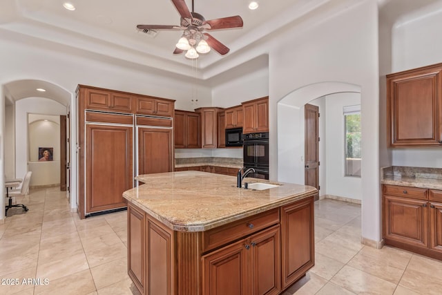 14619 E Desert Vista Trl, Scottsdale, AZ 85262 - kitchen with arched walkways, black appliances, a ceiling fan, a sink, and light stone countertops
