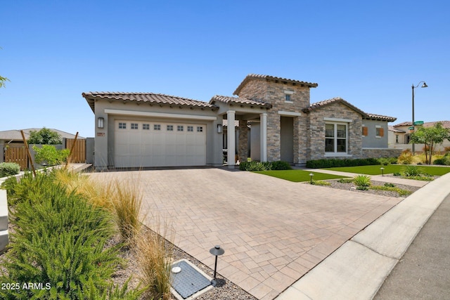 20797 W Rattler Rd, Buckeye, AZ 85396 - mediterranean / spanish house with an attached garage, decorative driveway, a tiled roof, stucco siding, and stone siding