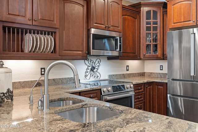 kitchen with glass insert cabinets, light stone countertops, and stainless steel appliances