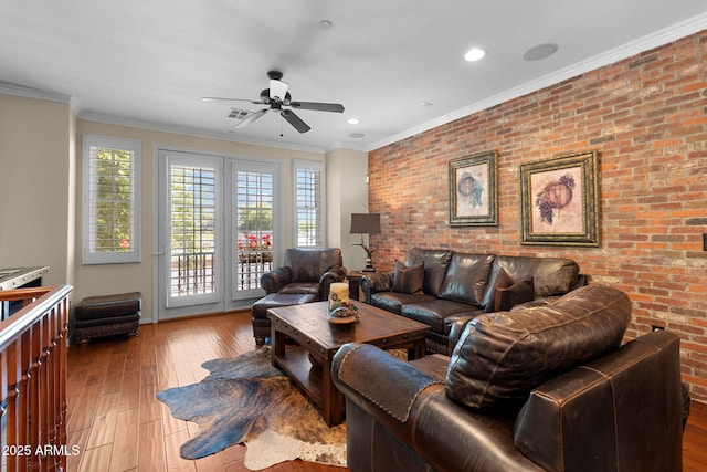 living area featuring a ceiling fan, hardwood / wood-style flooring, and brick wall