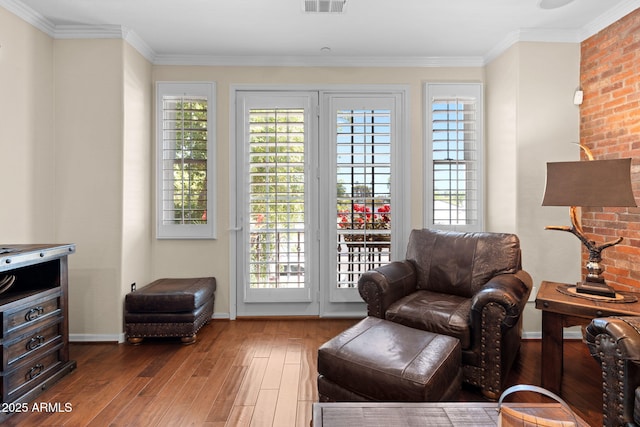 living area featuring baseboards, ornamental molding, hardwood / wood-style flooring, and visible vents
