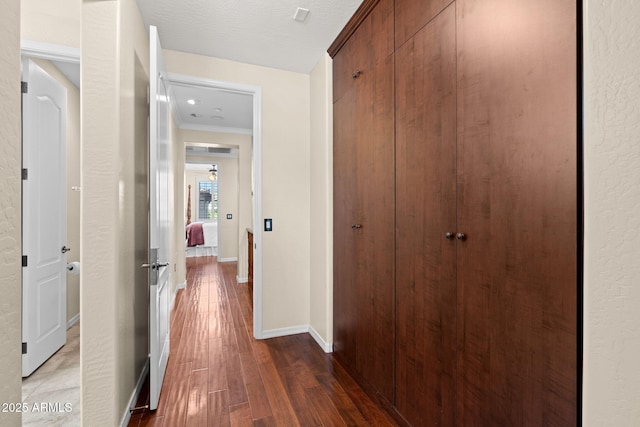 hall with baseboards, ornamental molding, and wood finished floors