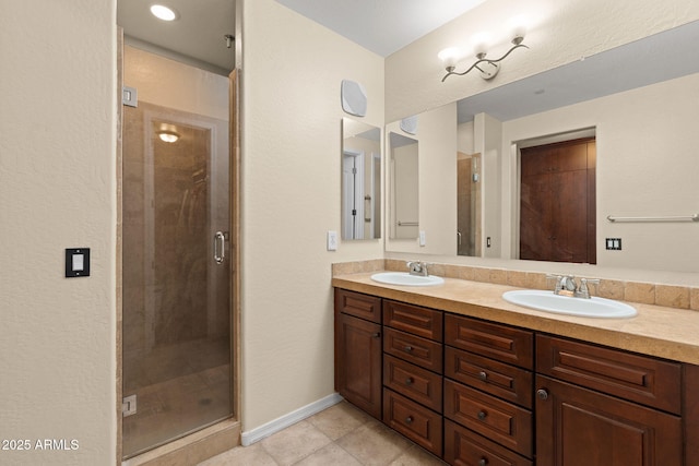 full bath featuring double vanity, a sink, tile patterned flooring, and a stall shower