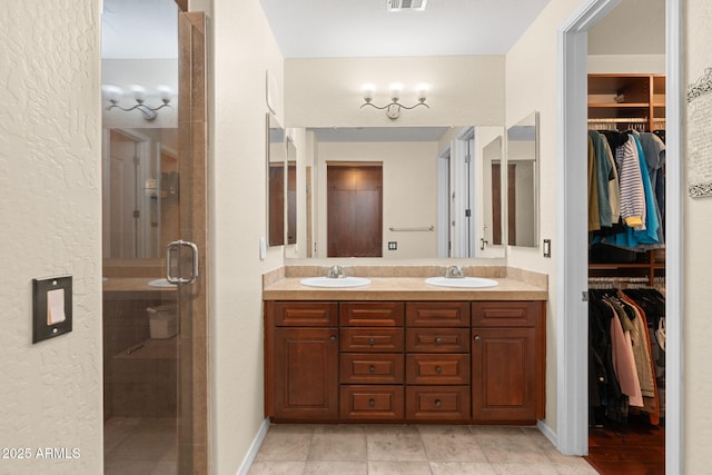 full bathroom featuring double vanity, a sink, a spacious closet, and a shower stall