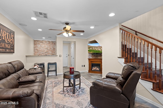 living area featuring visible vents, ornamental molding, a glass covered fireplace, recessed lighting, and a ceiling fan