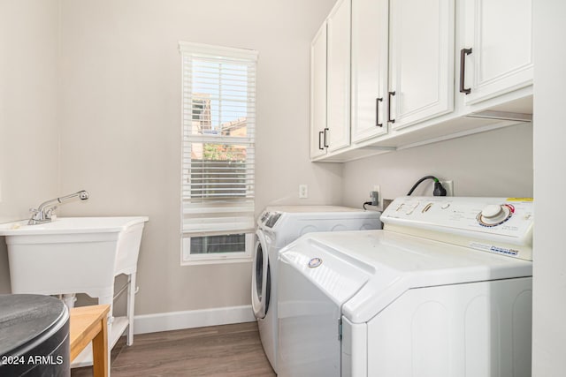 laundry area with cabinets, washing machine and dryer, and wood-type flooring