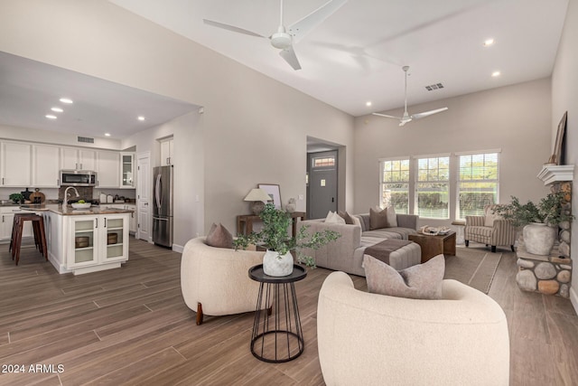 living room with a towering ceiling, dark hardwood / wood-style floors, and ceiling fan