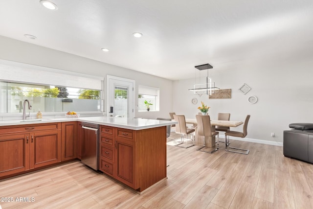 kitchen featuring sink, decorative light fixtures, kitchen peninsula, and light wood-type flooring