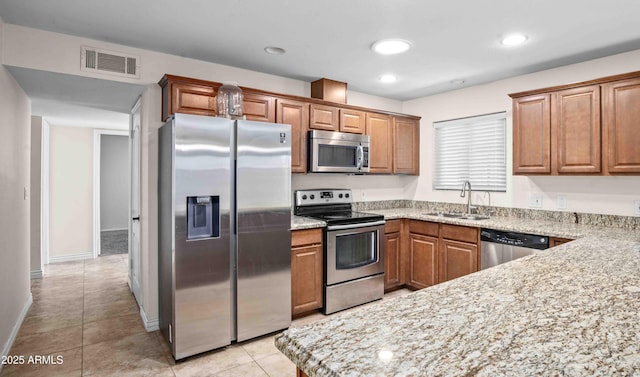 1158 N Barkley St, Mesa, AZ 85203 - kitchen with appliances with stainless steel finishes, brown cabinetry, light stone countertops, recessed lighting, and light tile patterned floors