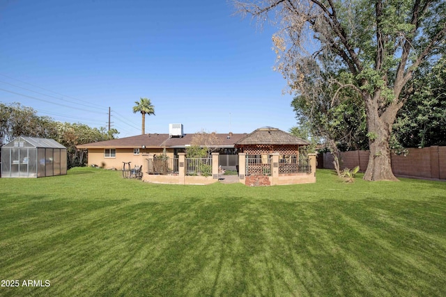 1158 N Barkley St, Mesa, AZ 85203 - back of house with a gazebo, a greenhouse, a fenced backyard, an outbuilding, and stucco siding
