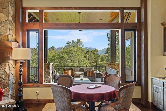 sunroom / solarium featuring a mountain view, wooden ceiling, and a healthy amount of sunlight