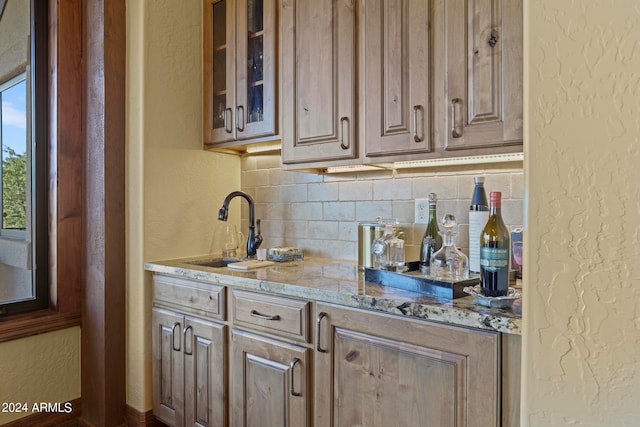 kitchen featuring light stone counters, backsplash, and sink