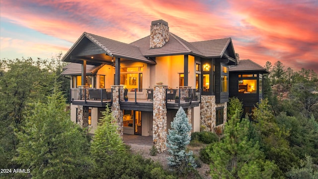 back house at dusk featuring a balcony