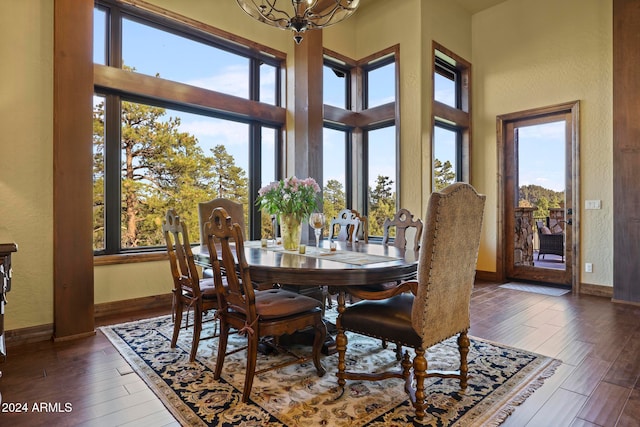 dining space with a towering ceiling, a notable chandelier, and dark hardwood / wood-style flooring