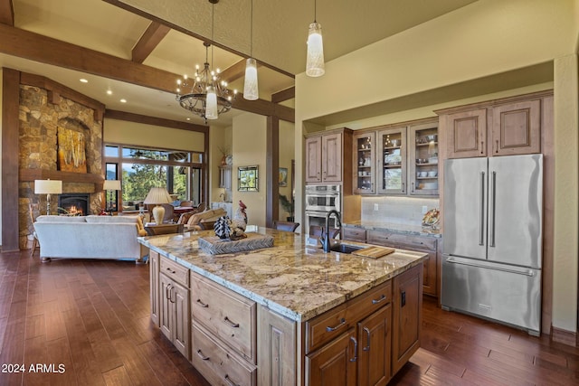 kitchen featuring sink, beam ceiling, a center island with sink, appliances with stainless steel finishes, and dark hardwood / wood-style flooring