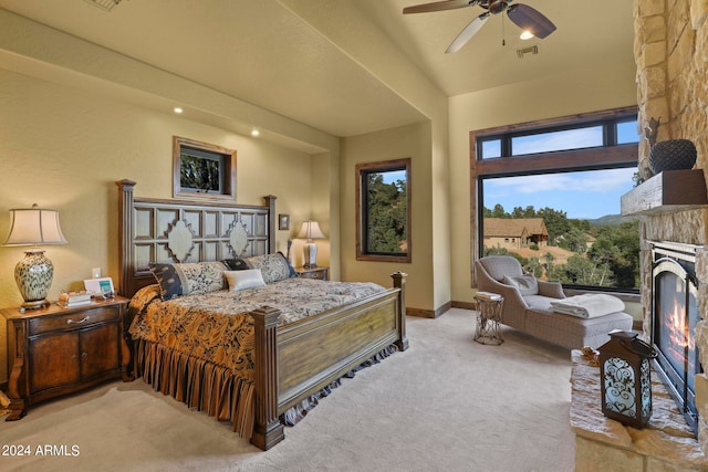 carpeted bedroom featuring ceiling fan and a fireplace