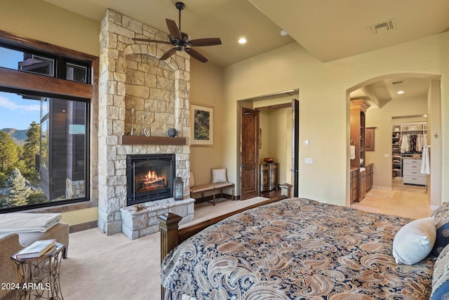 bedroom with ceiling fan, a fireplace, connected bathroom, and light carpet