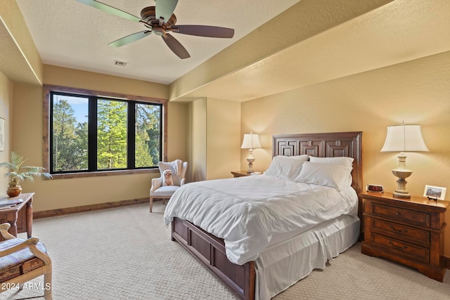 carpeted bedroom with ceiling fan and a textured ceiling