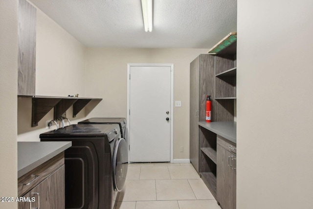 washroom featuring light tile patterned floors, separate washer and dryer, a textured ceiling, and cabinet space