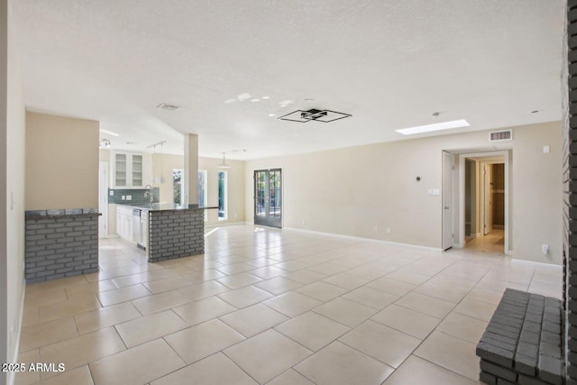 living area with light tile patterned floors, a textured ceiling, visible vents, and baseboards