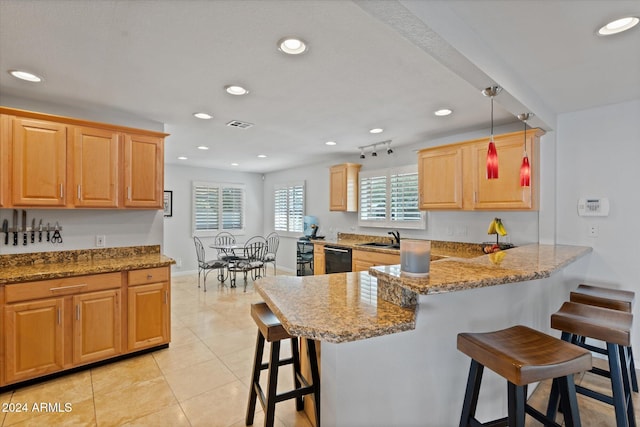 kitchen with kitchen peninsula, a kitchen breakfast bar, sink, light tile patterned floors, and decorative light fixtures