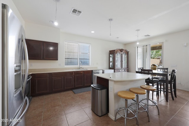 kitchen with stainless steel appliances, a breakfast bar, a sink, visible vents, and a center island