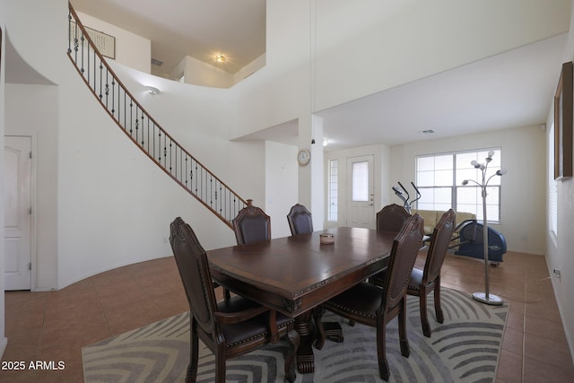 dining area with a high ceiling, stairway, and tile patterned flooring