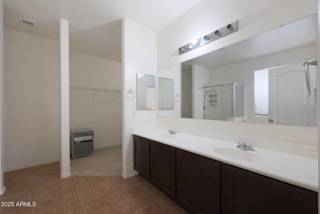 bathroom featuring a stall shower, a walk in closet, a sink, and double vanity