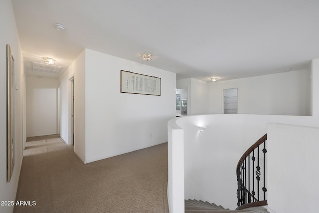 hallway with carpet, visible vents, and an upstairs landing