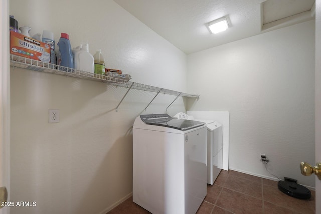 washroom with laundry area, dark tile patterned flooring, washing machine and dryer, and baseboards