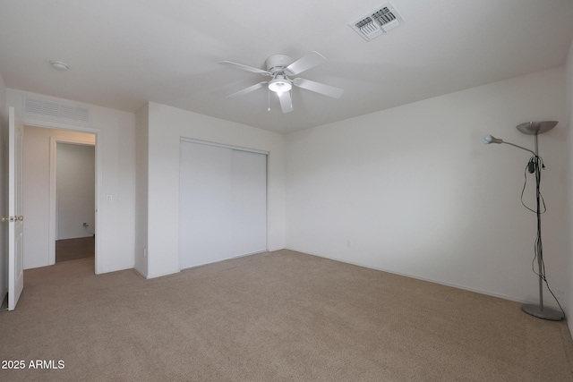 unfurnished bedroom featuring ceiling fan, visible vents, a closet, and light colored carpet