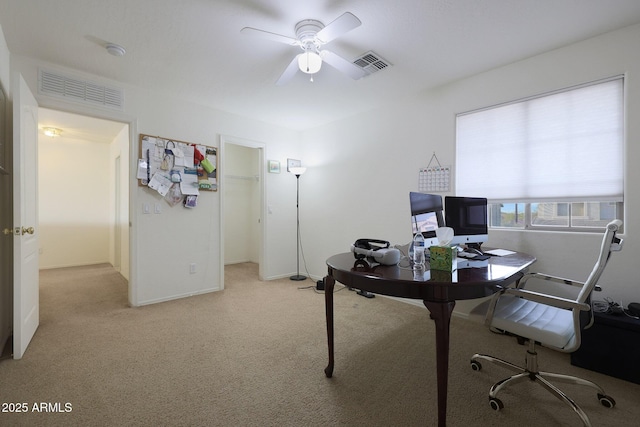 office featuring ceiling fan, visible vents, baseboards, and light colored carpet