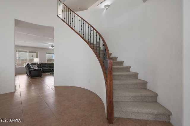 staircase with a towering ceiling and tile patterned floors