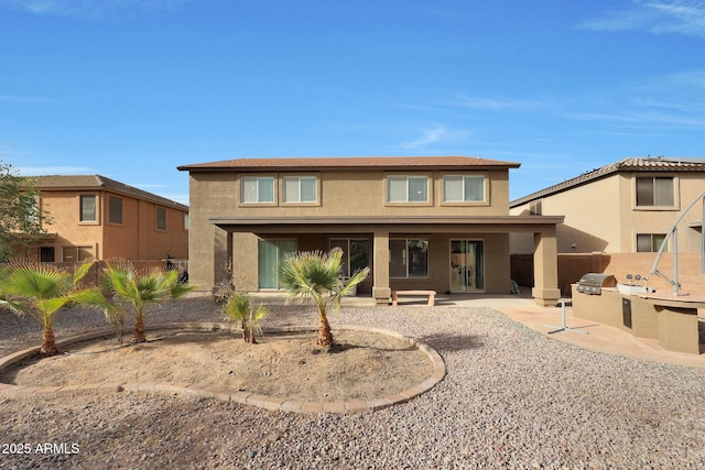 view of front facade with a patio area, fence, exterior kitchen, and stucco siding