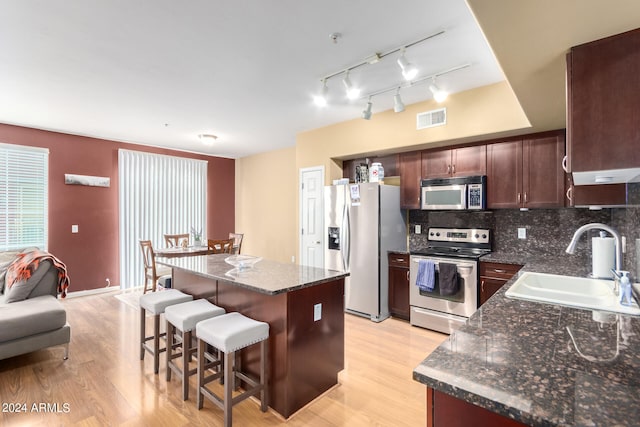 kitchen featuring tasteful backsplash, a kitchen island, sink, light hardwood / wood-style floors, and stainless steel appliances