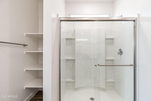 bathroom with wood-type flooring and a shower with shower door