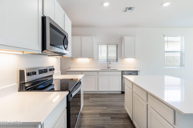 kitchen featuring a wealth of natural light, stainless steel appliances, sink, white cabinets, and dark hardwood / wood-style floors