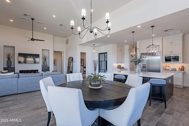 dining room with sink, a towering ceiling, and ceiling fan with notable chandelier