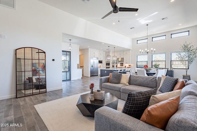 living room featuring ceiling fan with notable chandelier and a towering ceiling