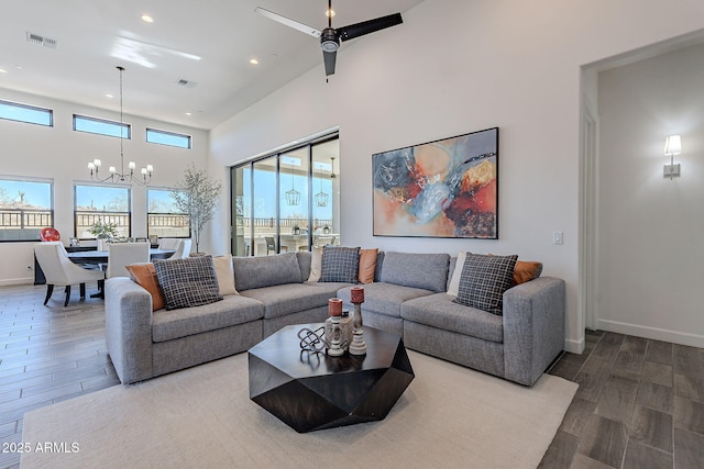 living room with a towering ceiling and ceiling fan with notable chandelier