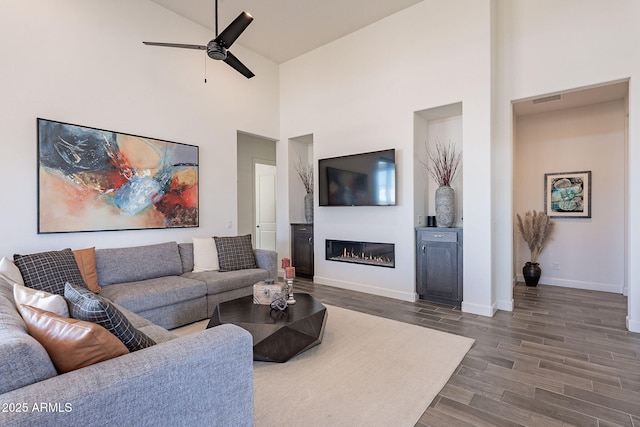 living room featuring ceiling fan, high vaulted ceiling, and dark hardwood / wood-style floors