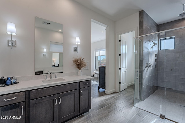 bathroom featuring a shower with shower door and vanity